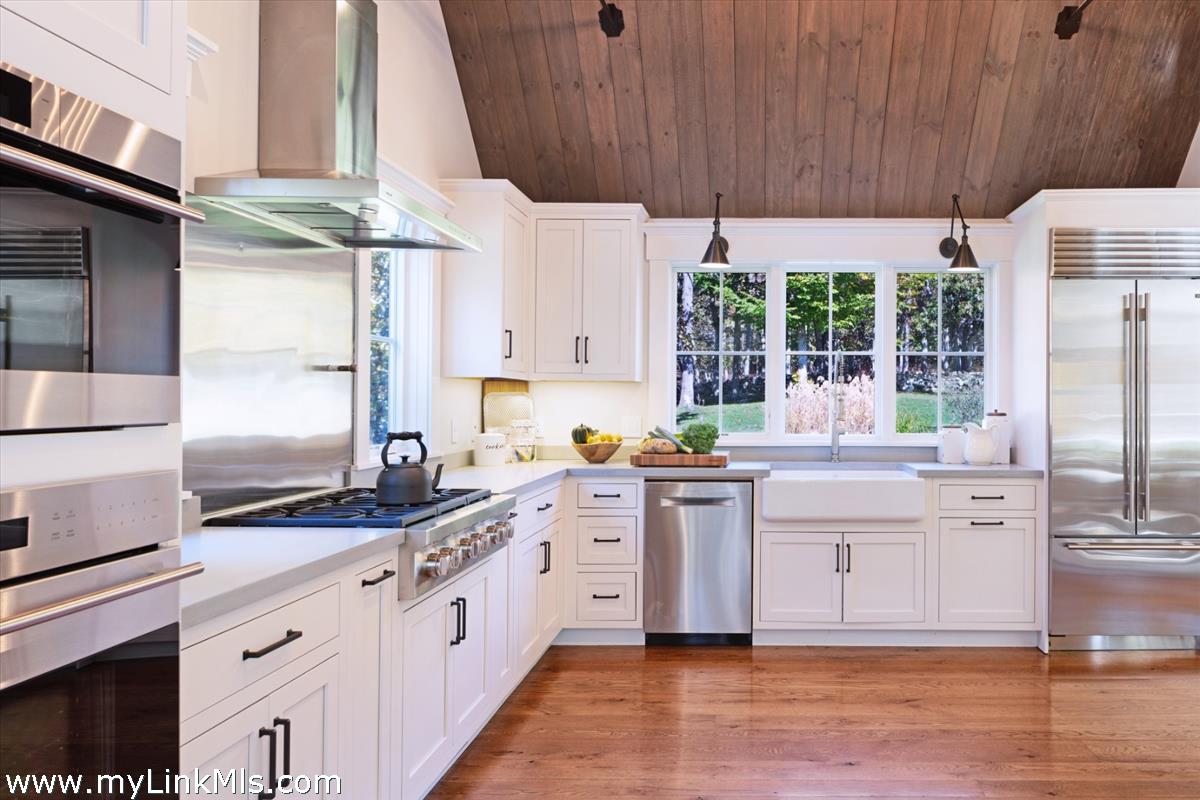27 Clambelly Road Chilmark, MA 02535 - Photo 11 of 39 a kitchen with stainless steel appliances a sink a stove and white cabinets next to a window