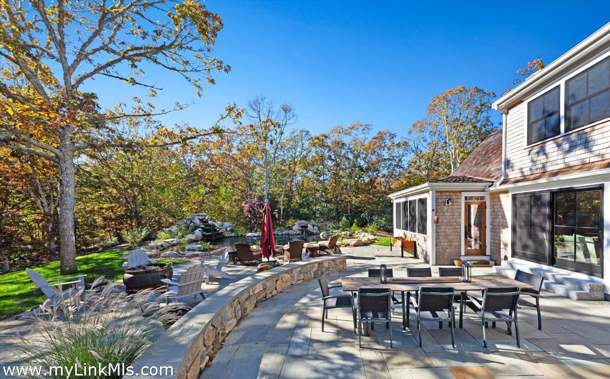 27 Clambelly Road Chilmark, MA 02535 - Photo 36 of 39 a view of a patio with dining table and chairs with a large tree