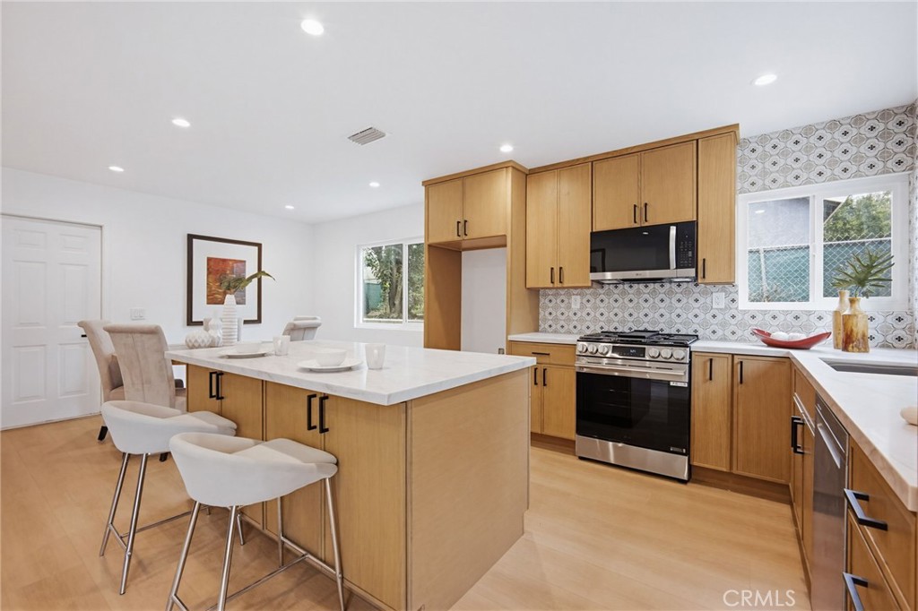 7355 Vineyard Avenue Rancho Cucamonga, CA 91730 - Photo 10 of 38 a kitchen with stainless steel appliances kitchen island granite countertop a sink and a stove top oven with wooden floor