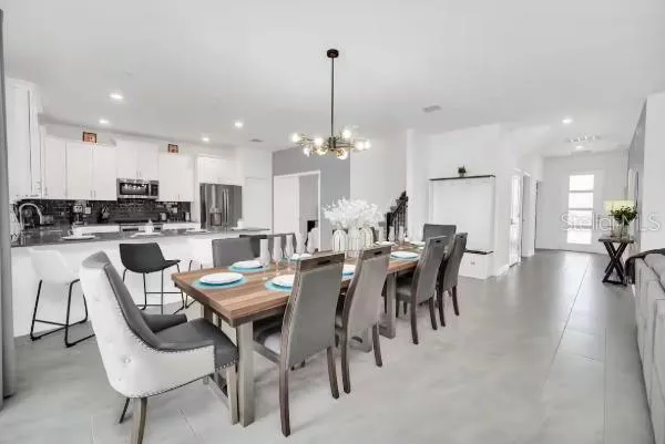 a dining room with furniture a chandelier and kitchen view