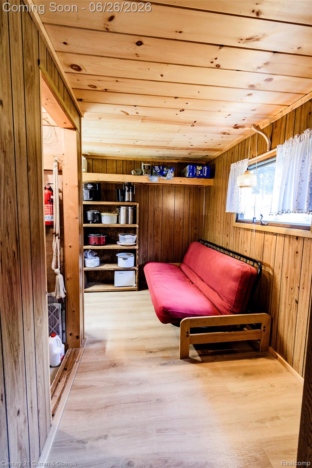 3270 Woods Road Harrison, MI 48625 - Photo 33 of 42 Interior space featuring wood-paneled walls and ceiling, wood-finish flooring, built-in shelving, and a single window with white curtains