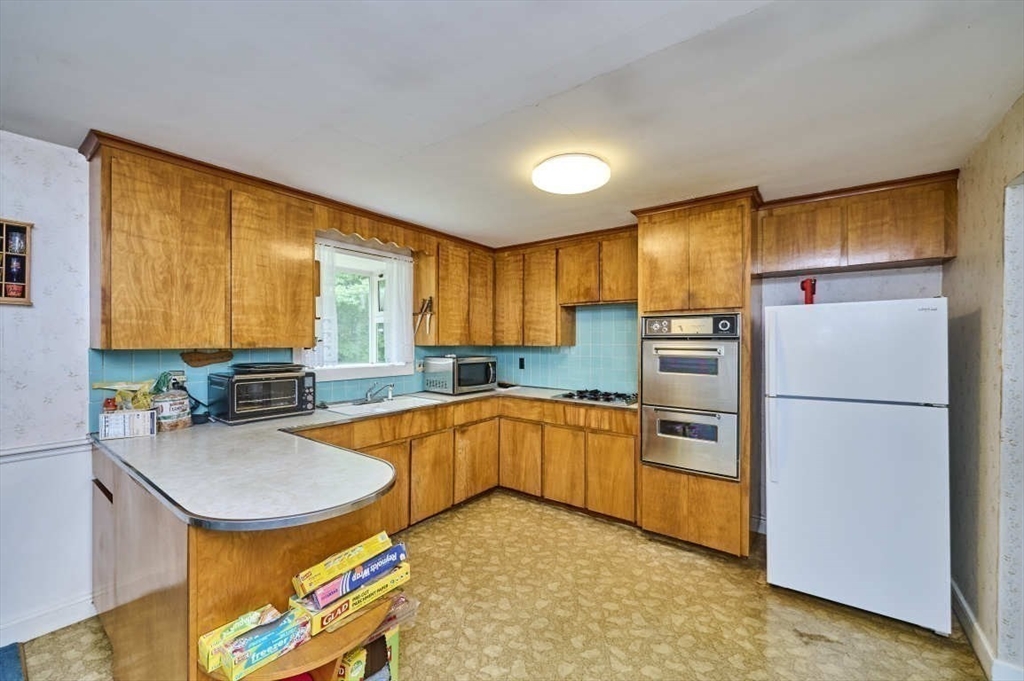 9 Bowman Road Billerica, MA 01821 - Photo 4 of 23 a kitchen with stainless steel appliances granite countertop a refrigerator a sink and a stove