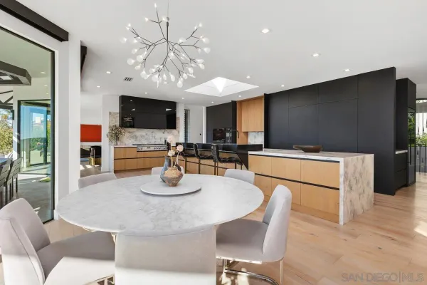 a kitchen with stainless steel appliances kitchen island granite countertop a refrigerator a stove a microwave oven a dining table and chairs with wooden floor