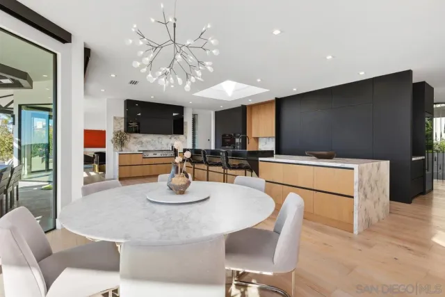 a kitchen with stainless steel appliances kitchen island granite countertop a refrigerator a stove a microwave oven a dining table and chairs with wooden floor