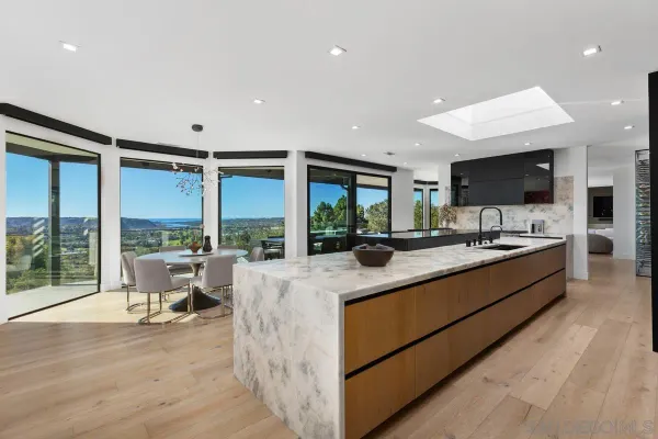 a large kitchen with kitchen island a large window in it