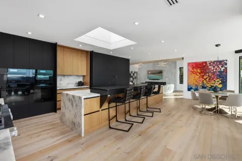 a view of a kitchen with dining table chairs refrigerator and sink