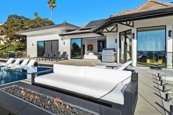 a view of a patio with couches table and chairs with wooden floor and fence