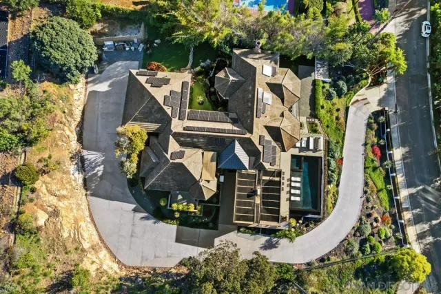 an aerial view of a house with swimming pool and large trees