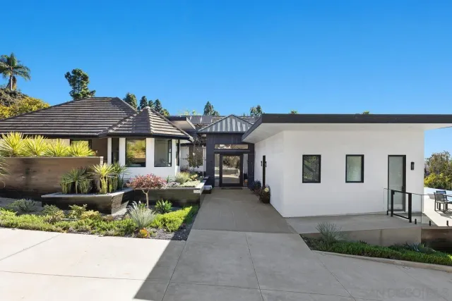 a front view of a house with a yard and potted plants