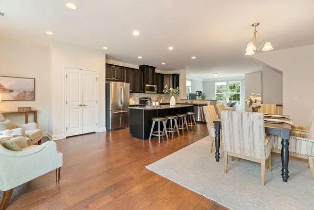 a dining room with stainless steel appliances kitchen island granite countertop a table chairs and a refrigerator