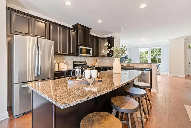 a kitchen with granite countertop kitchen island stainless steel appliances a refrigerator and a table