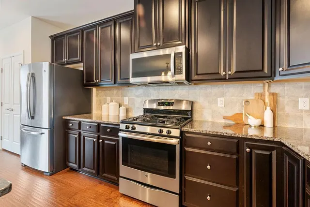 a kitchen with stainless steel appliances granite countertop a stove microwave and refrigerator