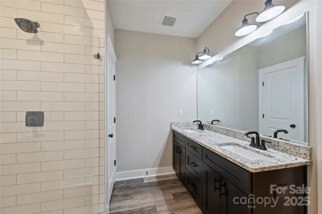 a bathroom with a granite countertop sink a large mirror and shower