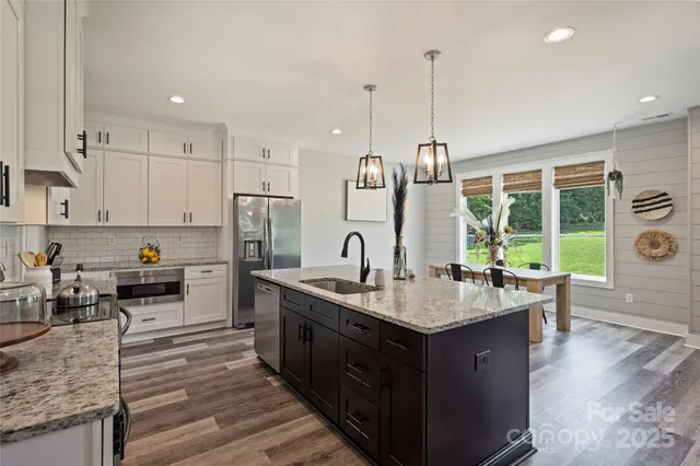 a kitchen with kitchen island granite countertop a stove and a wooden floors