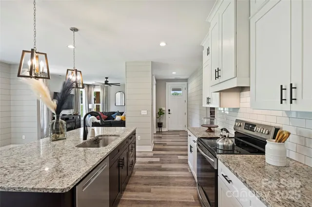 a kitchen with stainless steel appliances granite countertop a sink a stove and a wooden floors