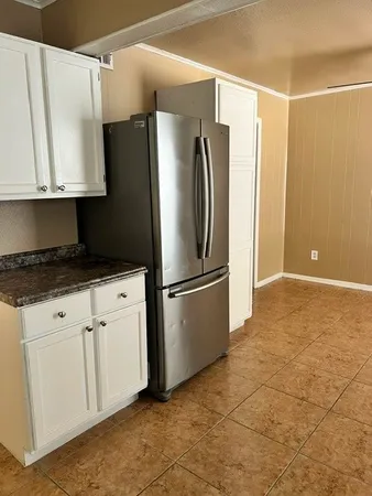 a kitchen with granite countertop white cabinets stainless steel appliances and a window