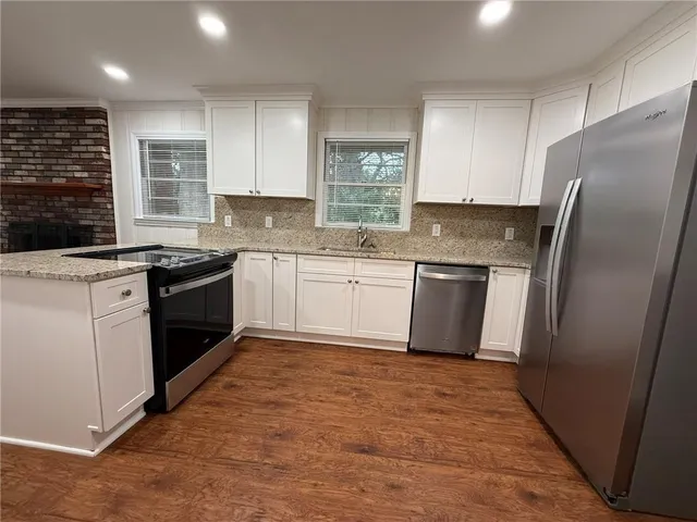 a kitchen with stainless steel appliances granite countertop a sink stove refrigerator and cabinets