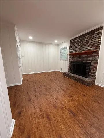 an empty room with wooden floor fireplace and windows