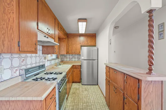 a kitchen with refrigerator a stove a sink dishwasher and wooden cabinets with wooden floor