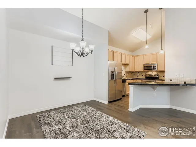 a kitchen with stainless steel appliances granite countertop a refrigerator a sink dishwasher a stove and white cabinets with wooden floor