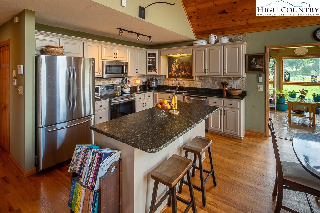 980 Scenic Drive Vilas, NC 28692 - Photo 11 of 42 a kitchen with stainless steel appliances granite countertop a refrigerator a stove top oven a sink dishwasher and white cabinets with wooden floor