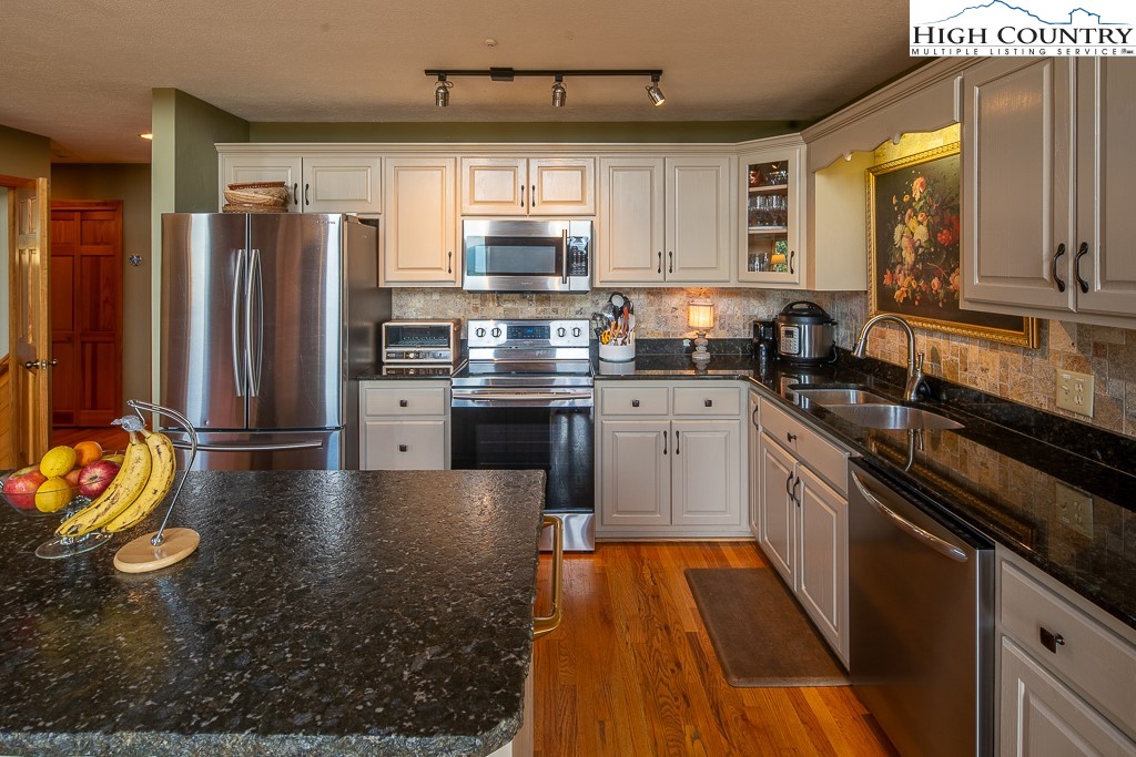 980 Scenic Drive Vilas, NC 28692 - Photo 13 of 42 a kitchen with stainless steel appliances granite countertop a refrigerator a sink dishwasher and white cabinets with wooden floor