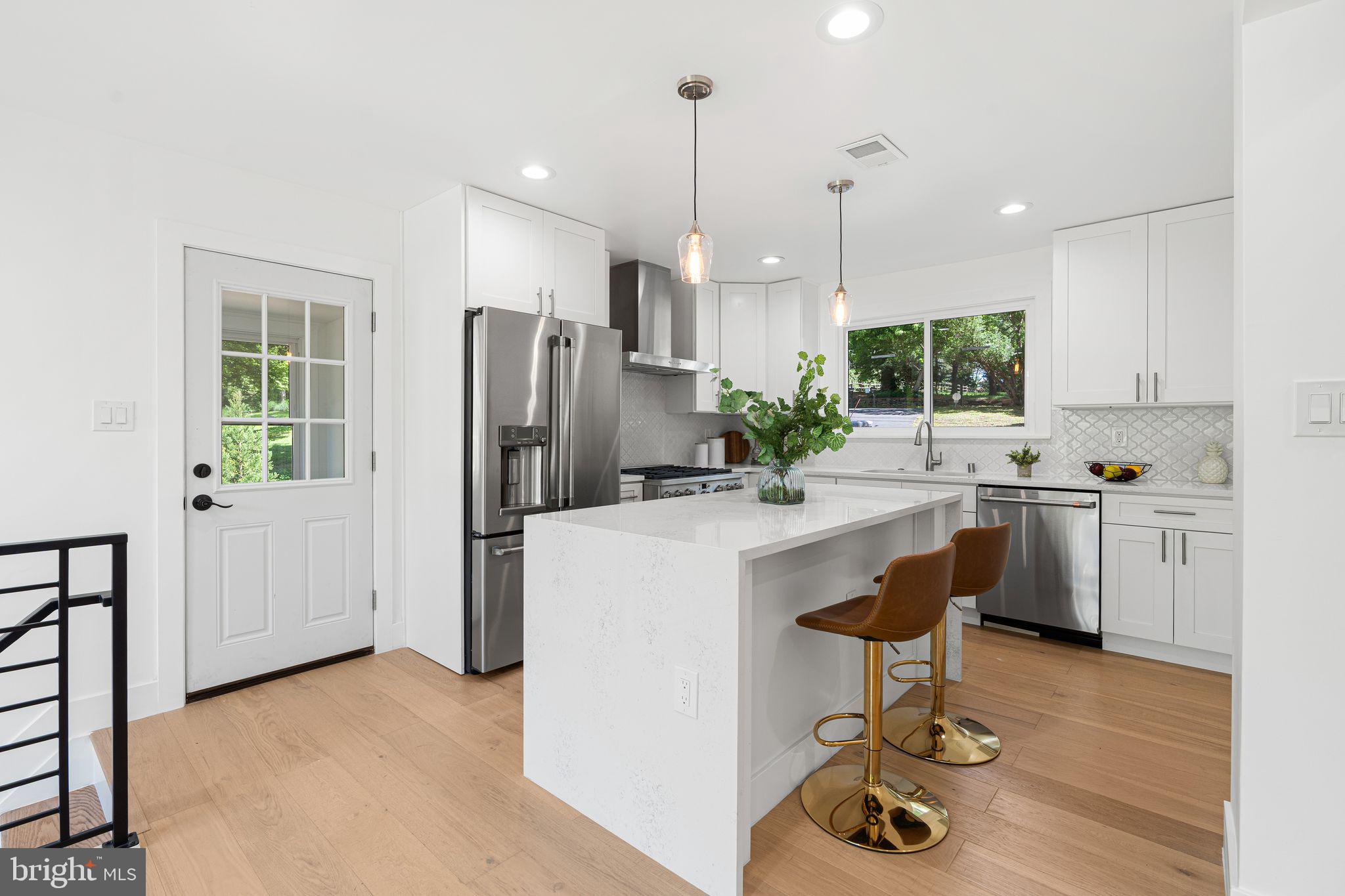 726 Darby Paoli Road Newtown Square, PA 19073 - Photo 26 of 55 a kitchen with kitchen island granite countertop a stove a refrigerator a oven a sink a dining table and chairs with wooden floor
