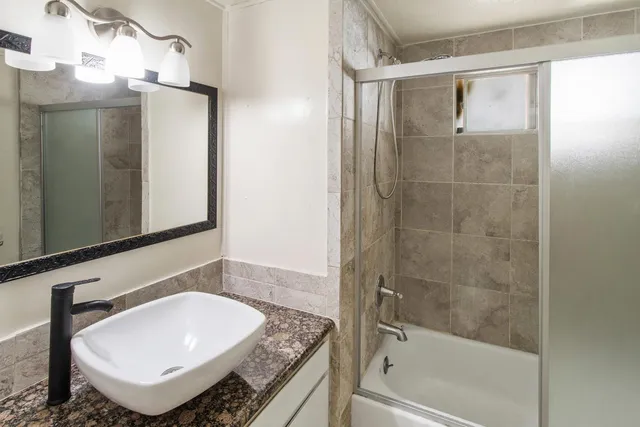 a bathroom with a granite countertop sink mirror and bathtub