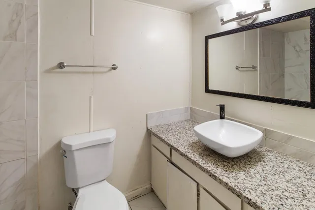 a bathroom with a granite countertop toilet sink and mirror