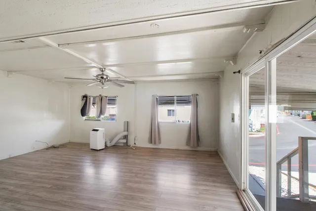a view of a room with wooden floor a ceiling fan and windows