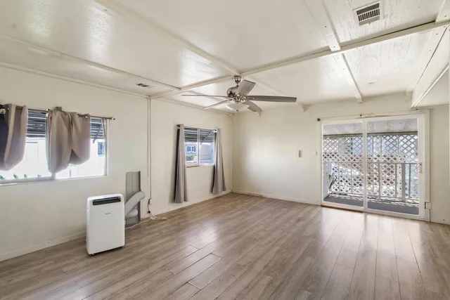 a view of an empty room with a window and wooden floor