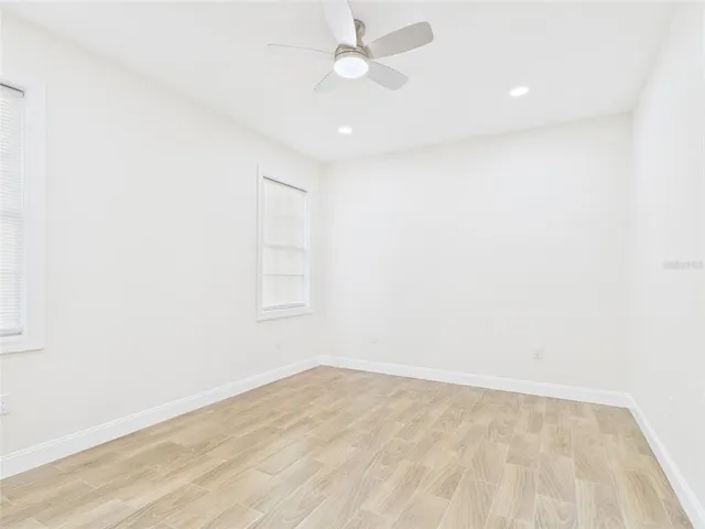 an empty room with wooden floor and fan