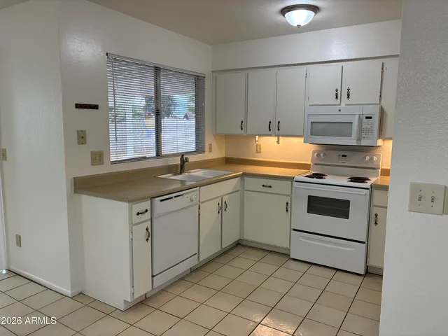 a kitchen with granite countertop white cabinets and white appliances