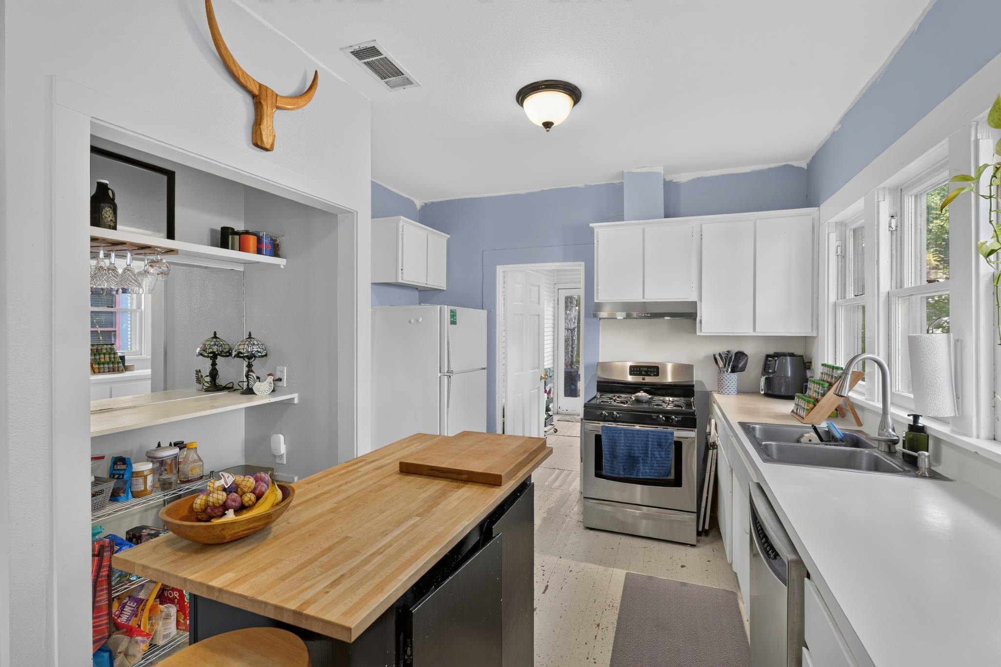 307 East 35th Street, Unit A Austin, TX 78705 - Photo 22 of 40 A compact kitchen with an eat-in island, stainless steel appliances, and ample natural light from generous windows.