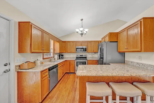 a kitchen with stainless steel appliances granite countertop a sink dishwasher stove and refrigerator with wooden floor