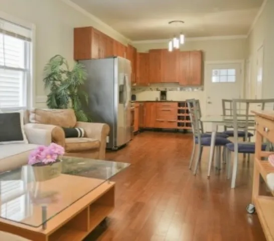 a kitchen with stainless steel appliances granite countertop a refrigerator a stove and a dining table with wooden floor