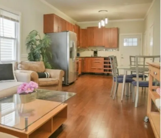 a kitchen with stainless steel appliances granite countertop a refrigerator a oven a sink a dining table and chairs with wooden floor