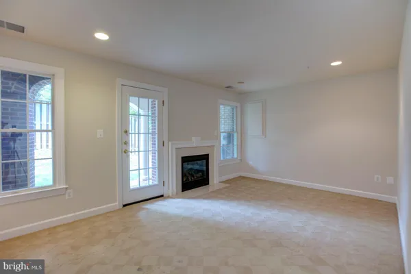 an empty room with windows and fireplace