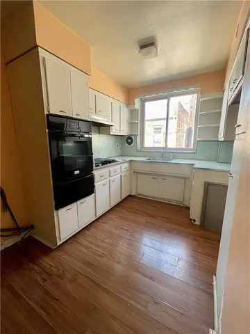 a kitchen with wooden floors and white stainless steel appliances