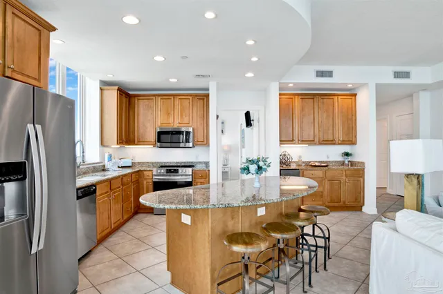 a kitchen with stainless steel appliances granite countertop a refrigerator a stove a sink a dining table and chairs with wooden floor