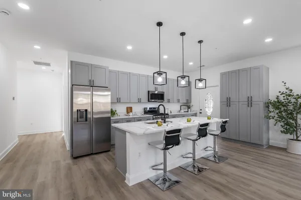 a kitchen with stainless steel appliances kitchen island granite countertop a dining table chairs stove and refrigerator