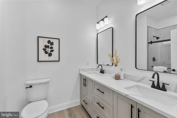 a bathroom with a toilet sink double vanity and mirror