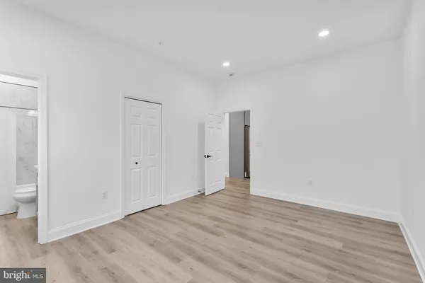 a view of an empty room with wooden floor and a bathroom