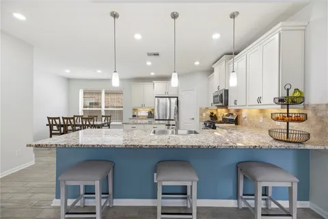 a kitchen with granite countertop a sink a counter space appliances and a cabinets