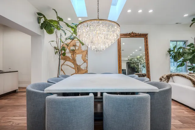 a dining room with wooden floor a chandelier a wooden table and chairs
