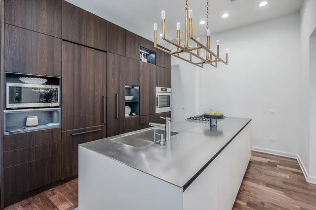 a kitchen with kitchen island granite countertop stainless steel appliances a sink and a refrigerator