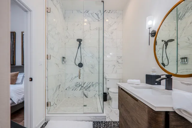 a bathroom with a granite countertop sink a toilet a mirror and shower