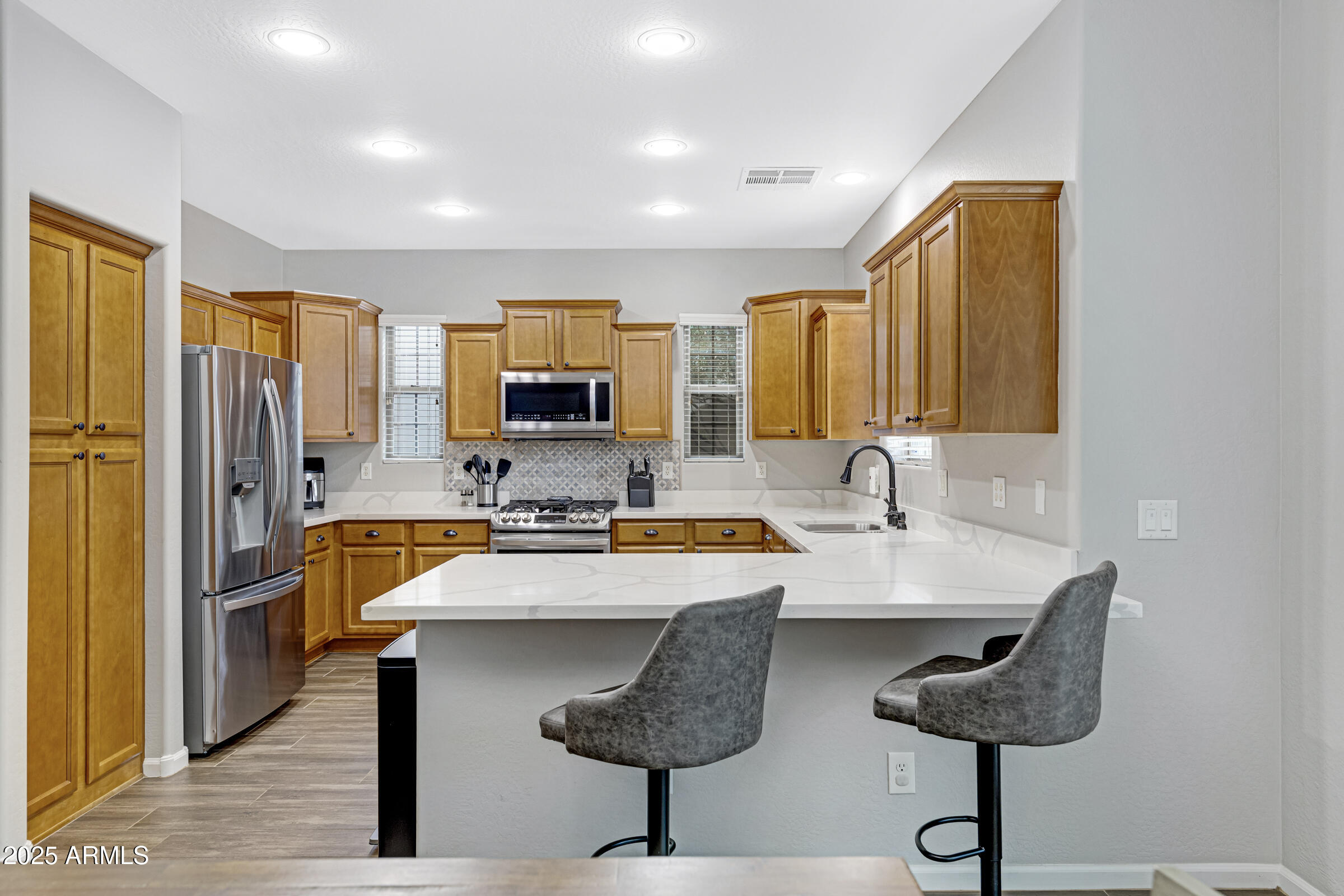 15366 West Bloomfield Road Surprise, AZ 85379 - Photo 24 of 48 a kitchen with stainless steel appliances granite countertop a sink a stove a refrigerator cabinets and a dining table with wooden floor