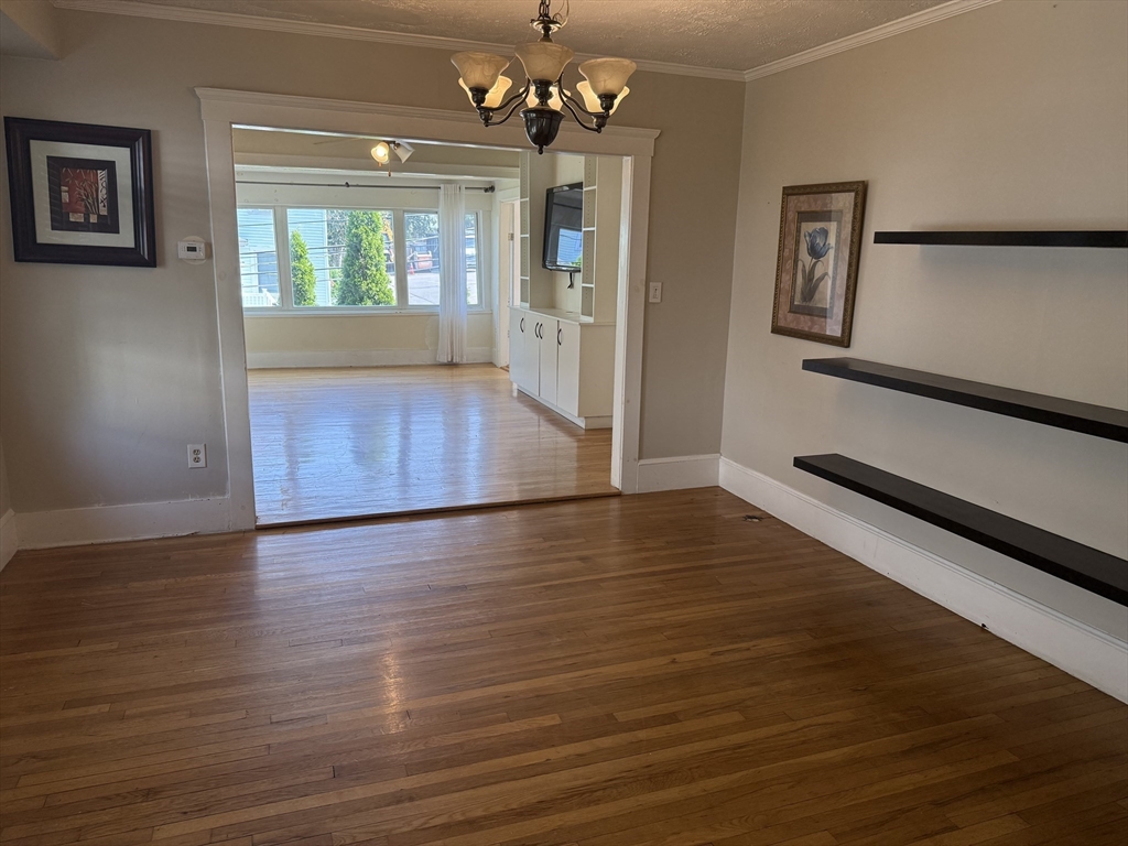 a view of an empty room with window and wooden floor