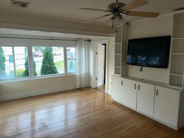a view of hallway with wooden floor and fan